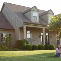 lady and her dog sitting on the lawn of a house